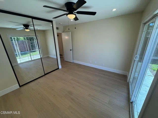a view of empty room with wooden floor and fan