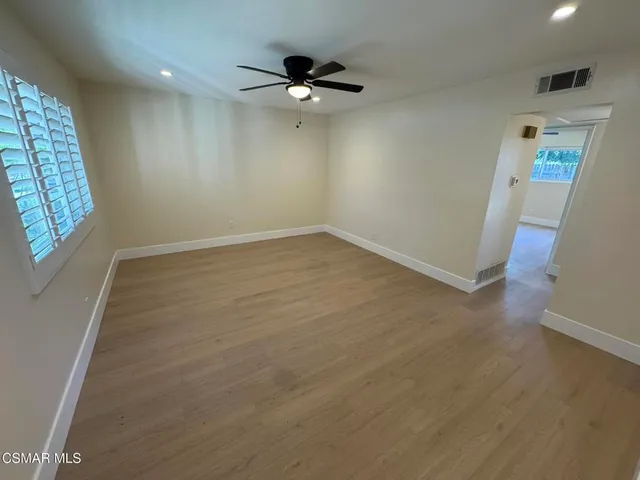 an empty room with windows and fan