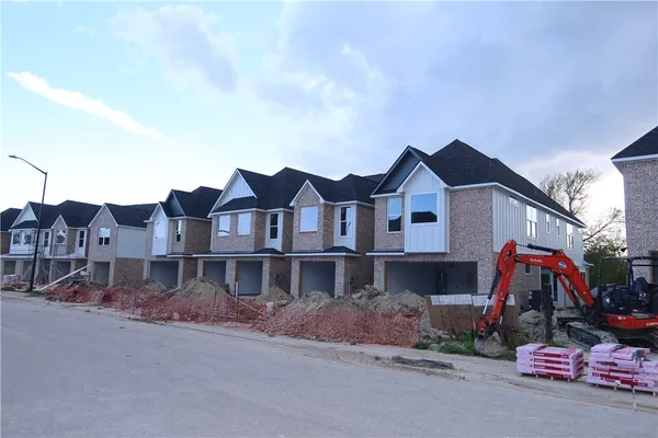a view of a white house next to a road with big trees