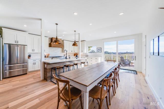 a kitchen with granite countertop a table chairs stainless steel appliances and wooden floor