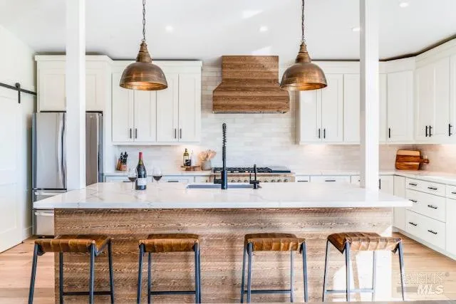 a kitchen with stainless steel appliances granite countertop a stove a sink and white cabinets with wooden floor