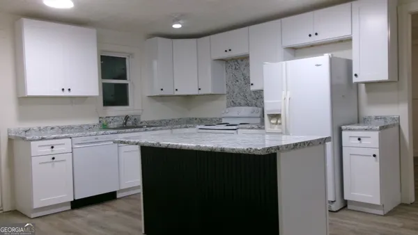 a kitchen with a counter top space cabinets and wooden floor