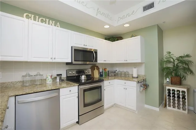 a kitchen with granite countertop white cabinets and white appliances