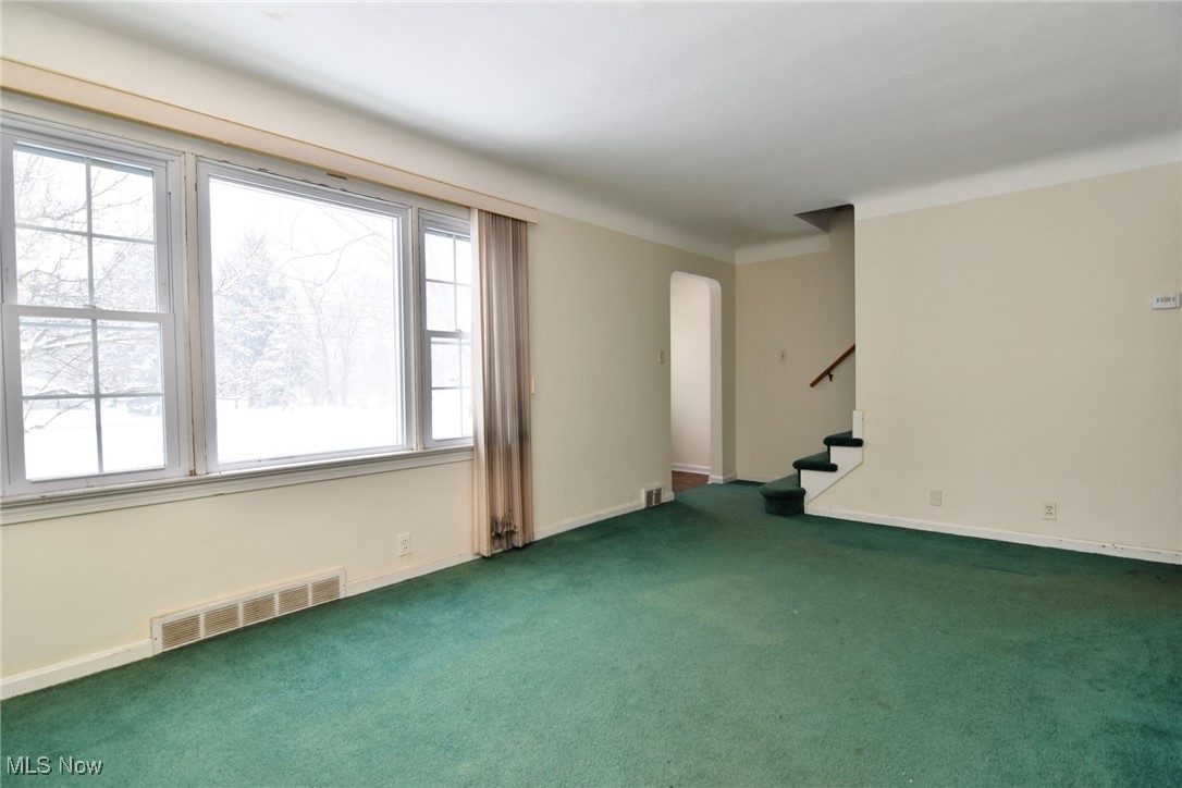 6308 Highland Road Cleveland, OH 44143 - Photo 10 of 40 Carpeted empty room featuring stairway, baseboards, visible vents, and arched walkways