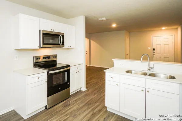 a kitchen with a sink and a stove top oven with wooden floor
