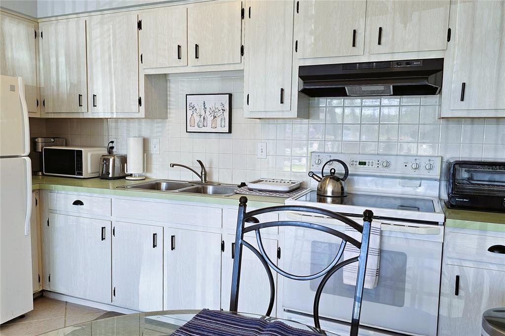 4318 Tahitian Gardens Circle, Unit B Holiday, FL 34691 - Photo 12 of 28 a kitchen with stainless steel appliances granite countertop a stove a sink and a white cabinets