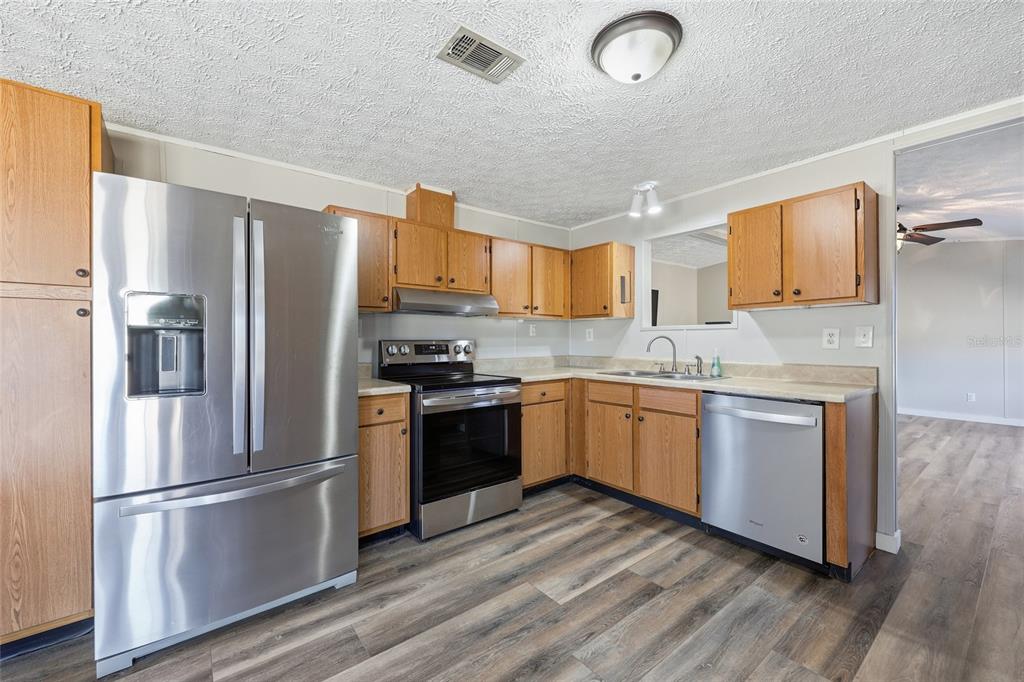 7119 Northeast 24th Loop High Springs, FL 32643 - Photo 6 of 35 a kitchen with a refrigerator cabinets and wooden floor