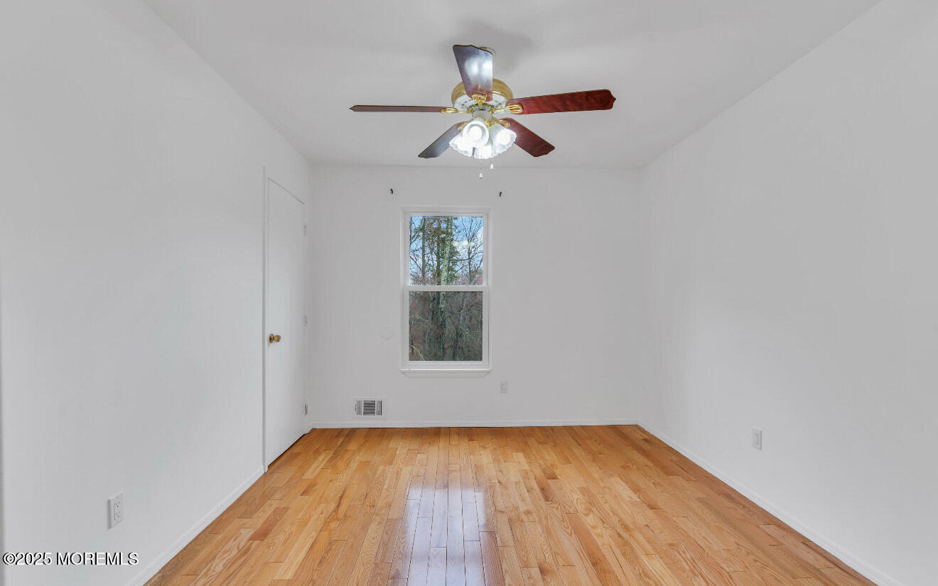 115 Leesville Road Jackson, NJ 08527 - Photo 14 of 15 an empty room with wooden floor chandelier fan and windows