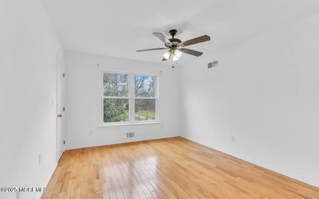 an empty room with a window and a fan
