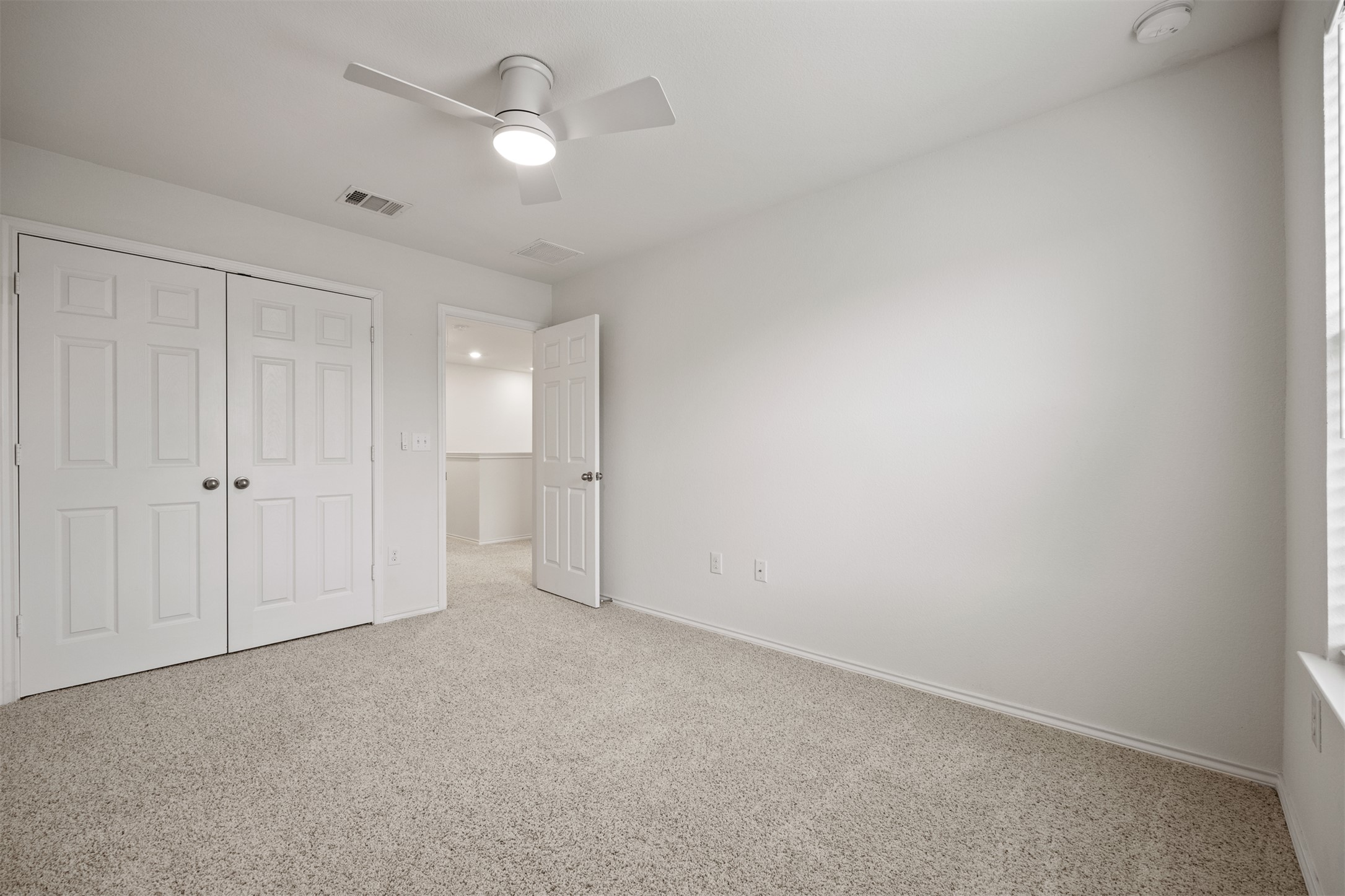 7009 Nutria Run Austin, TX 78744 - Photo 12 of 15 A well-lit room featuring soft carpet and a modern ceiling fan, offering a comfortable personal space.