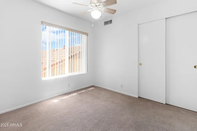 an empty room with a window and a fan