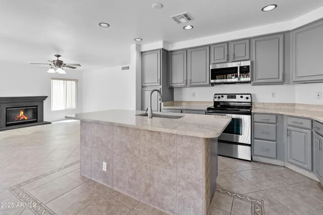 a kitchen with stainless steel appliances granite countertop a stove top oven a sink a refrigerator and white cabinets