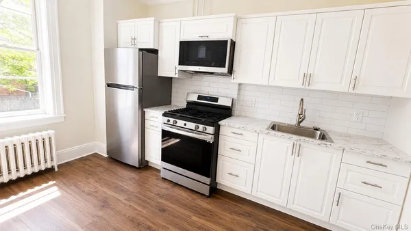 a kitchen with white cabinets stainless steel appliances and wooden floor