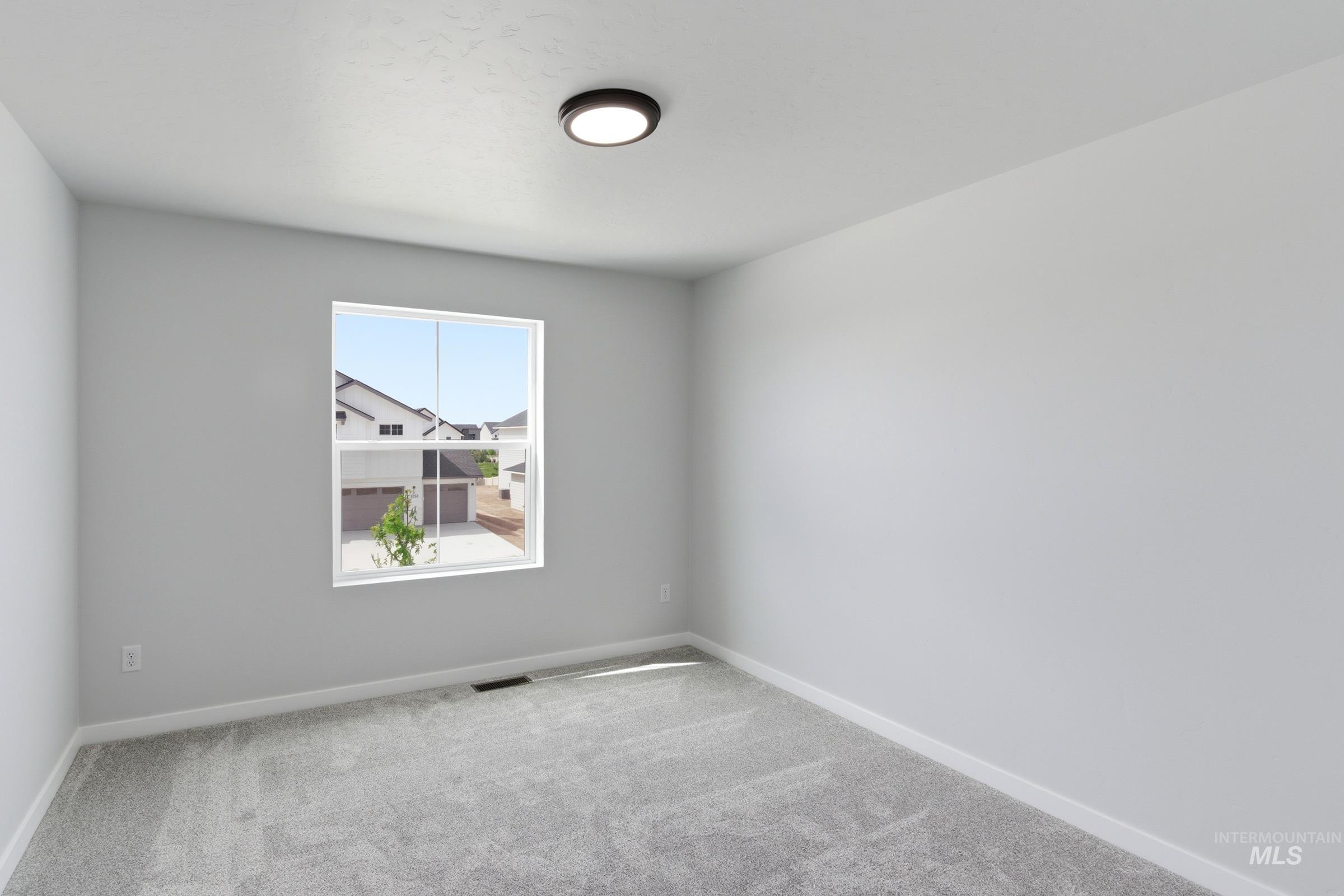 12829 Decatur Street Nampa, ID 83651 - Photo 24 of 33 Spacious room featuring light gray carpeting, neutral wall finishes, a bright window, and a modern flush-mount ceiling light