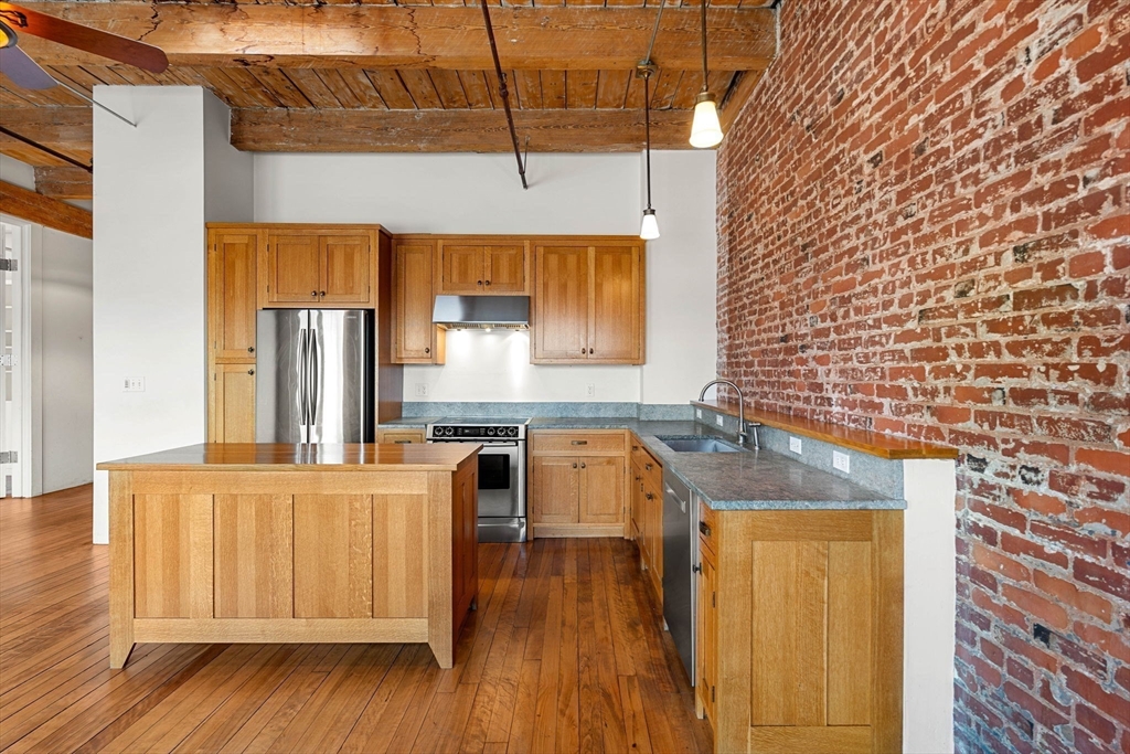 a kitchen with granite countertop a sink a stove and wooden floor