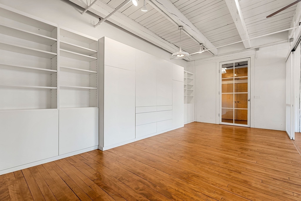 249 A Street, Unit 66 Boston, MA 02210 - Photo 12 of 26 a view of an empty room with wooden floor and a window