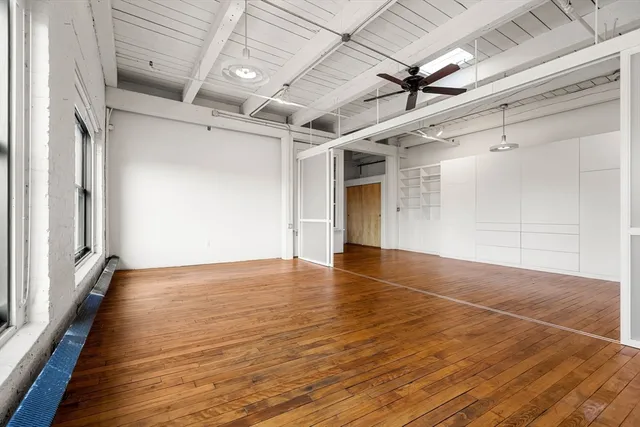 a view of empty room with wooden floor and fan