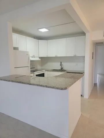 a kitchen with granite countertop a sink a stove a refrigerator and white cabinets