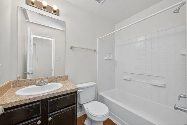 a bathroom with a granite countertop sink toilet a mirror and shower