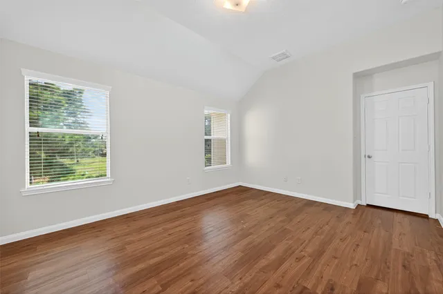 an empty room with wooden floor and windows