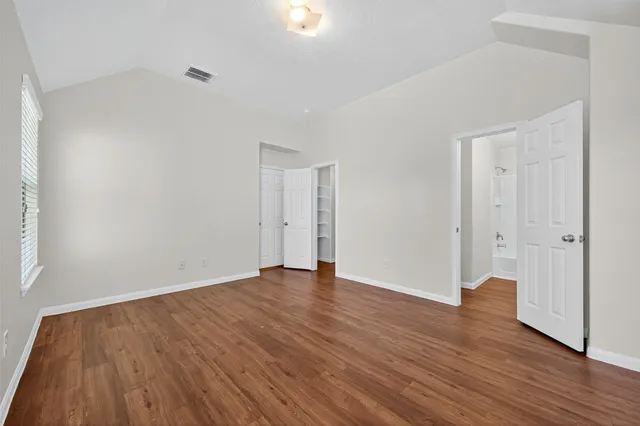 a view of an empty room with wooden floor and closet