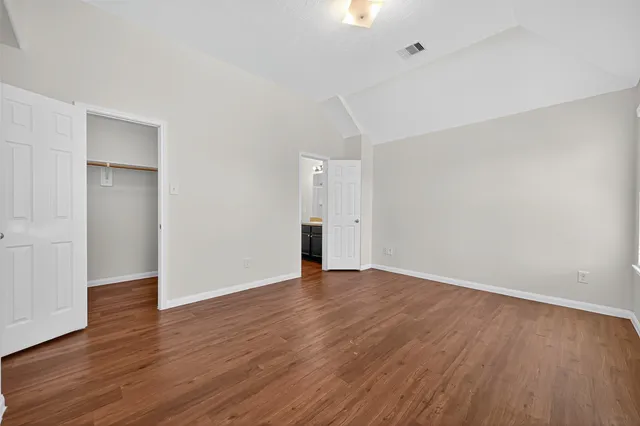 a view of an empty room with wooden floor and closet