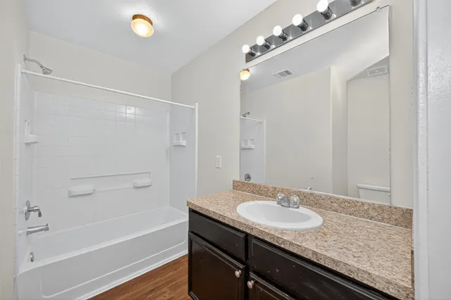 a bathroom with a granite countertop sink a mirror and a bathtub