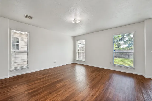 an empty room with wooden floor and windows