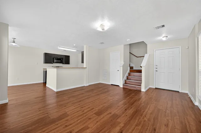 a view of an empty room with wooden floor and a fireplace