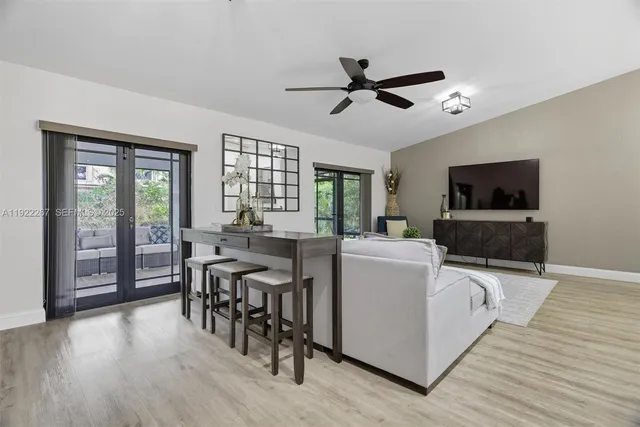 a living room with furniture a flat screen tv and a floor to ceiling window