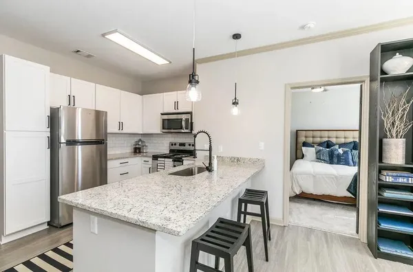 a kitchen with stainless steel appliances granite countertop a refrigerator a sink dishwasher a stove and white cabinets with wooden floor