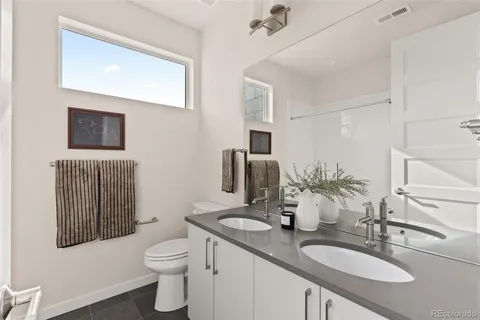 a bathroom with a granite countertop toilet sink and mirror
