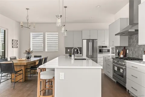 a kitchen with stainless steel appliances a stove a sink a kitchen island and couches with wooden floor