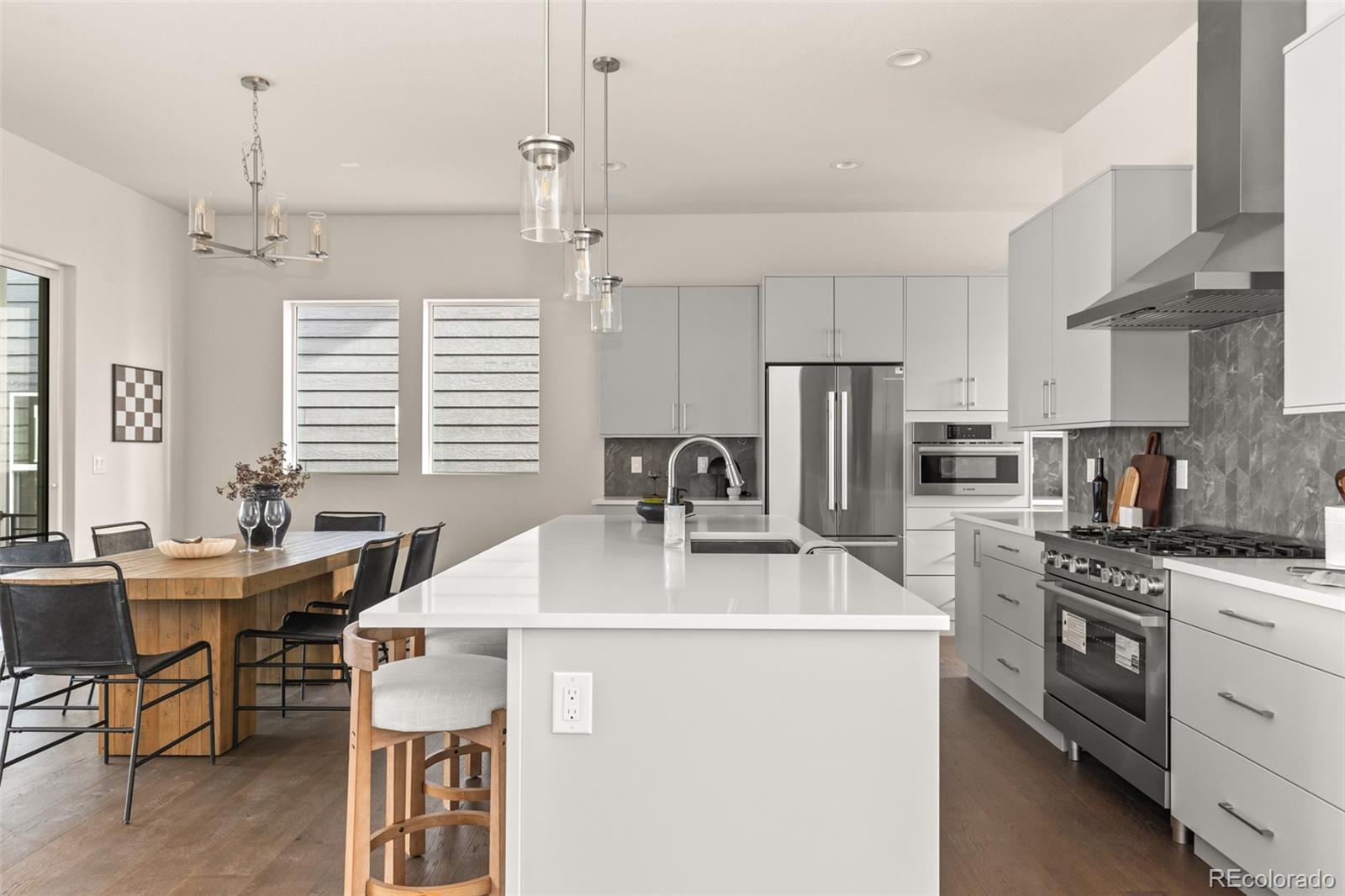 11332 Alla Breve Lone Tree, CO 80134 - Photo 6 of 50 a kitchen with stainless steel appliances a stove a sink a kitchen island and couches with wooden floor