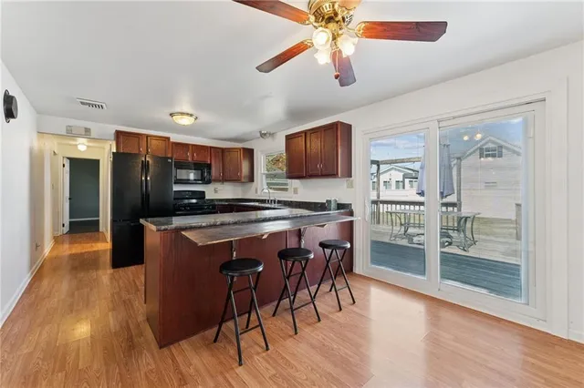 a kitchen with stainless steel appliances kitchen island granite countertop a refrigerator a stove a microwave oven a sink with island and chairs