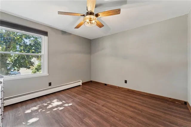 a view of empty room with wooden floor and fan