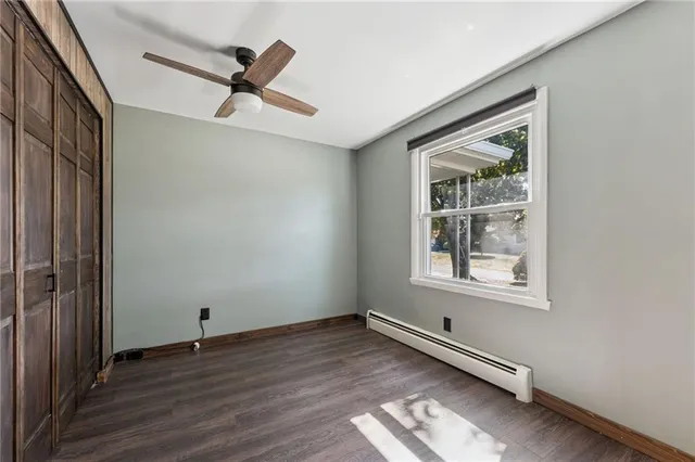 an empty room with wooden floor cabinet and windows