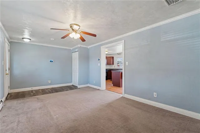 a view of an empty room and a ceiling fan and window