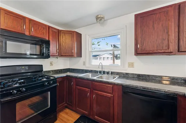 a kitchen with granite countertop a sink stove and microwave