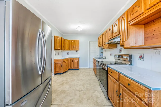 a kitchen with stainless steel appliances granite countertop a refrigerator a stove and a sink