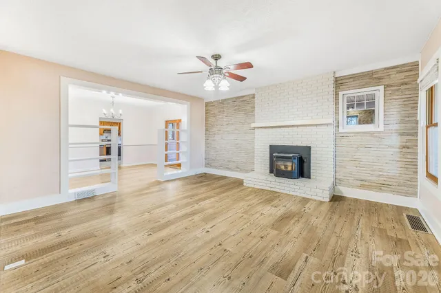 a view of a livingroom with wooden floor a fireplace and windows