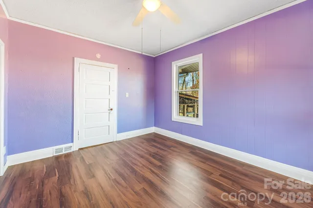 an empty room with wooden floor chandelier and windows