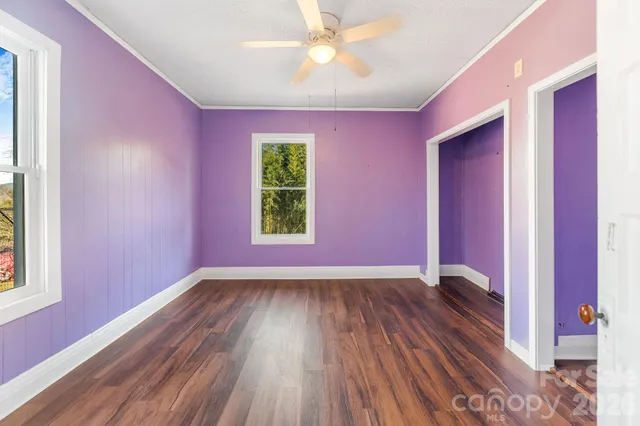 a view of an empty room with window and wooden floor