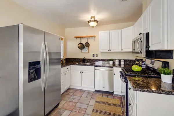 a kitchen with stainless steel appliances granite countertop a refrigerator a stove and a sink