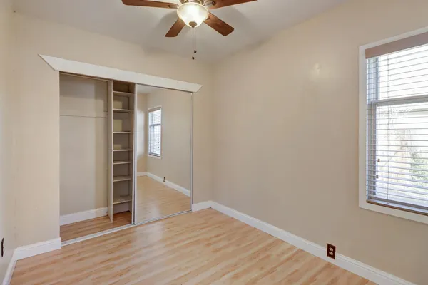 an empty room with wooden floor chandelier and windows