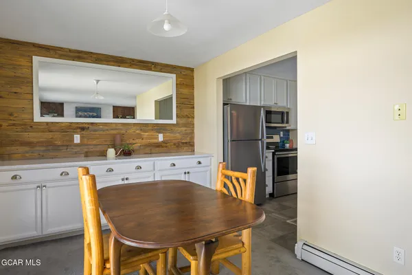 a kitchen with stainless steel appliances granite countertop a refrigerator a stove a sink and white cabinets with wooden floor