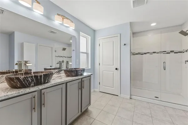 a bathroom with a granite countertop sink two mirror and shower