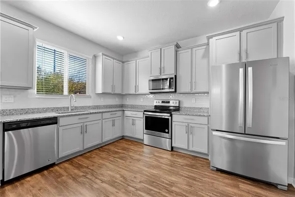 a kitchen with white cabinets stainless steel appliances a sink and a window