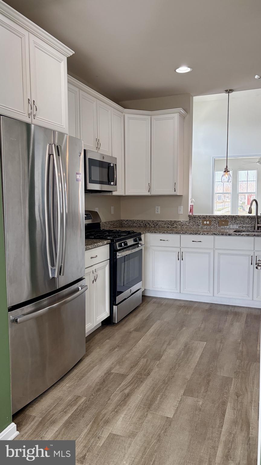 301 Arch Street Milton, DE 19968 - Photo 6 of 34 a kitchen with granite countertop a refrigerator a sink and white cabinets