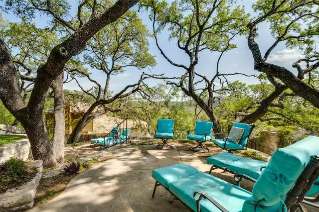 a backyard of a house with table and chairs under a large tree